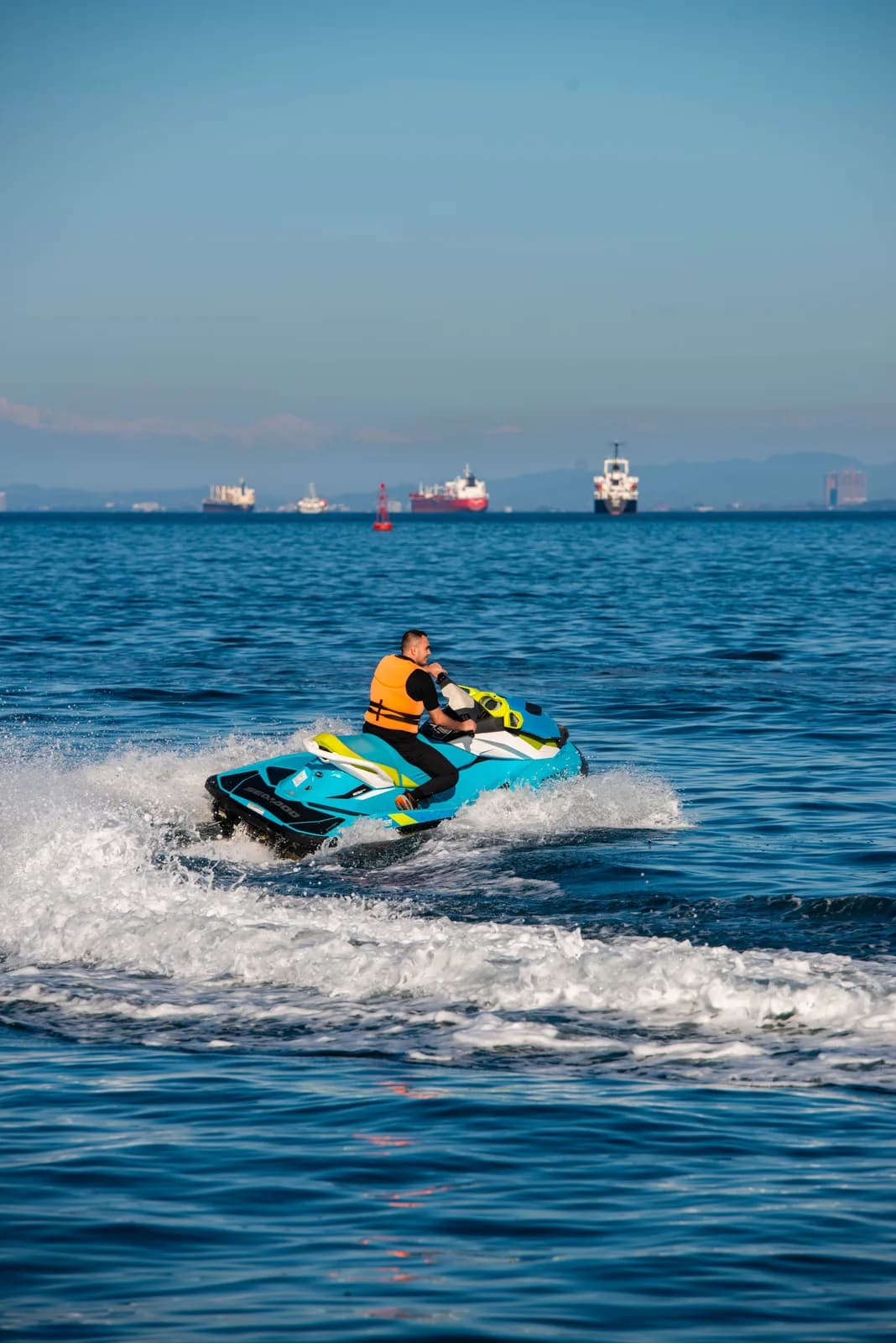 A rider in a life jacket crossing the wake on a Sea-Doo jet ski