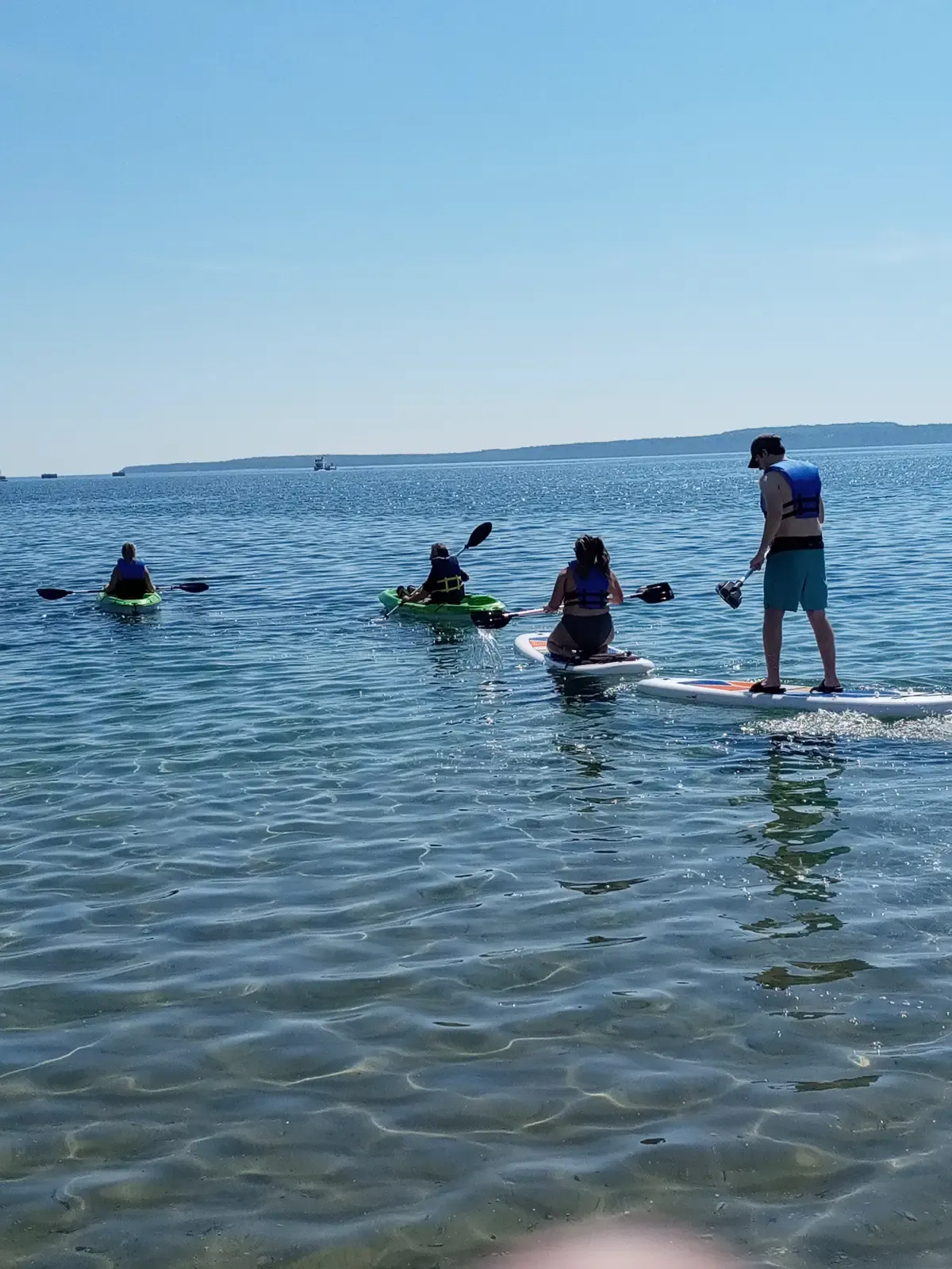 Renters paddling kayaks and a stand-up paddleboard on the Straits of Mackinac